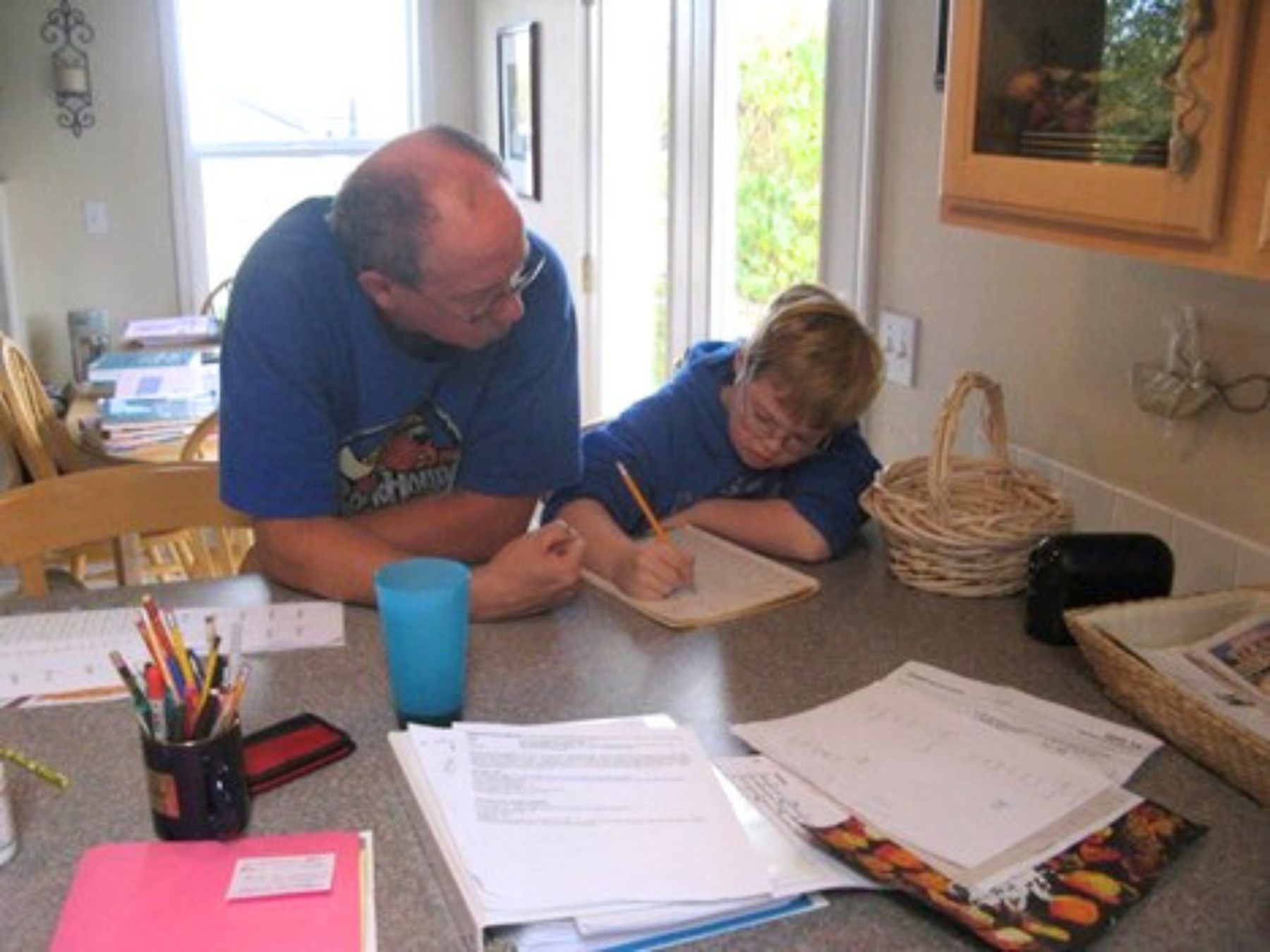 Student writing at a wooden desk with pencil in hand completing a science worksheet.